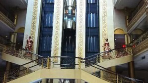 A multi-level atrium with a central elevator, ornate columns, and statues on the upper levels. - Pacific Palace Hotel (Batam)