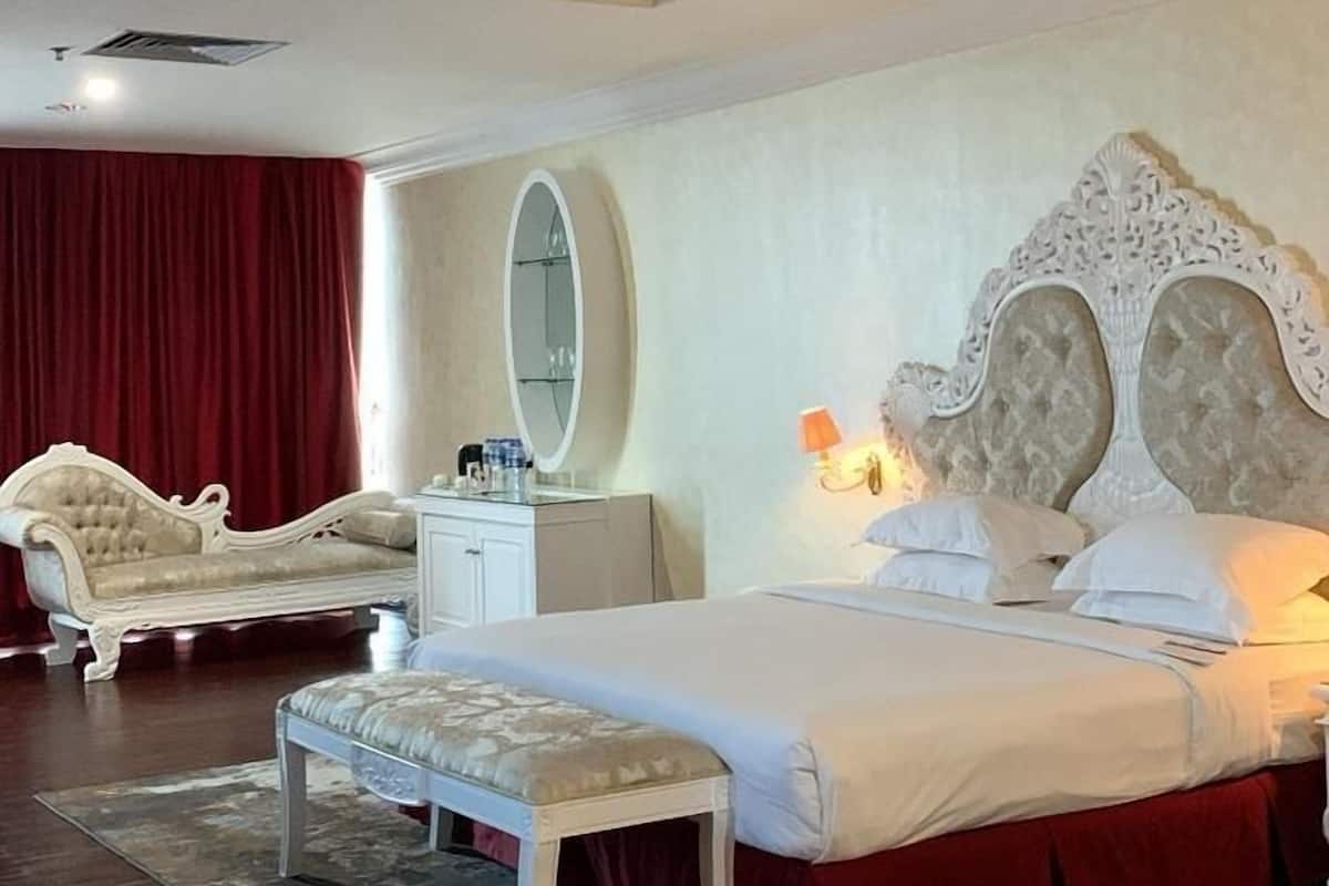 A spacious bedroom with a large bed, a vanity, and a red curtain.
