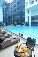 Una piscina interior con sillas de descanso y una mesa con fruta y una bebida.