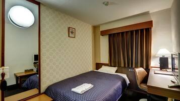 Habitación de hotel con una cama grande, un escritorio con computadora, una silla, un espejo y una ventana con cortinas.