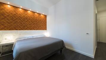A modern hotel room with a bed, a wooden accent wall, and a bedside table.