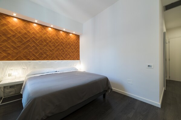Una habitación de hotel moderna con una cama, un panel de madera decorativo y una mesita de noche.