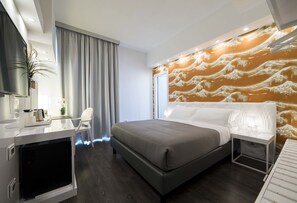 A modern hotel room with a large bed, a desk with a flat-screen TV, and a wall with a wave pattern design. - Hotel Montestella (Salerno)