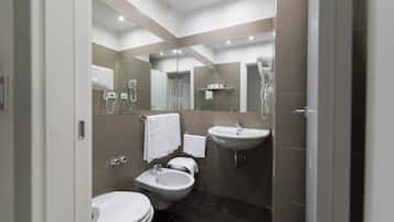 Une salle de bain moderne équipée de toilettes, d’un bidet, d’un lavabo et d’un grand miroir.