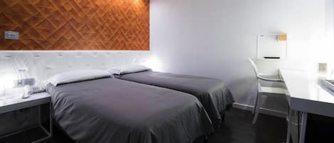 Habitación de hotel con dos camas, un escritorio, una silla y una pared con diseño geométrico.
