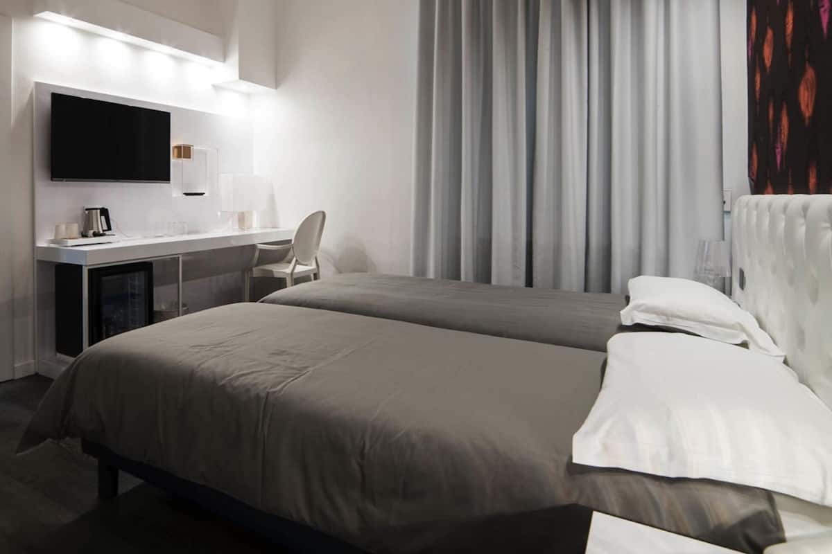 A hotel room with a bed, a desk with a TV, and a wardrobe.
