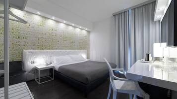 A modern hotel room with a bed, a desk, and a chair.