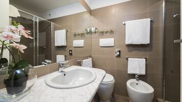 Une salle de bain moderne avec un grand miroir, un lavabo en marbre, des toilettes et un bidet.