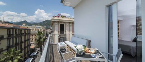 A balcony with a dining table, chairs, and a sofa.