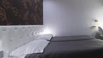 A modern hotel room with a large bed, a bedside telephone, and a wall-mounted light fixture.