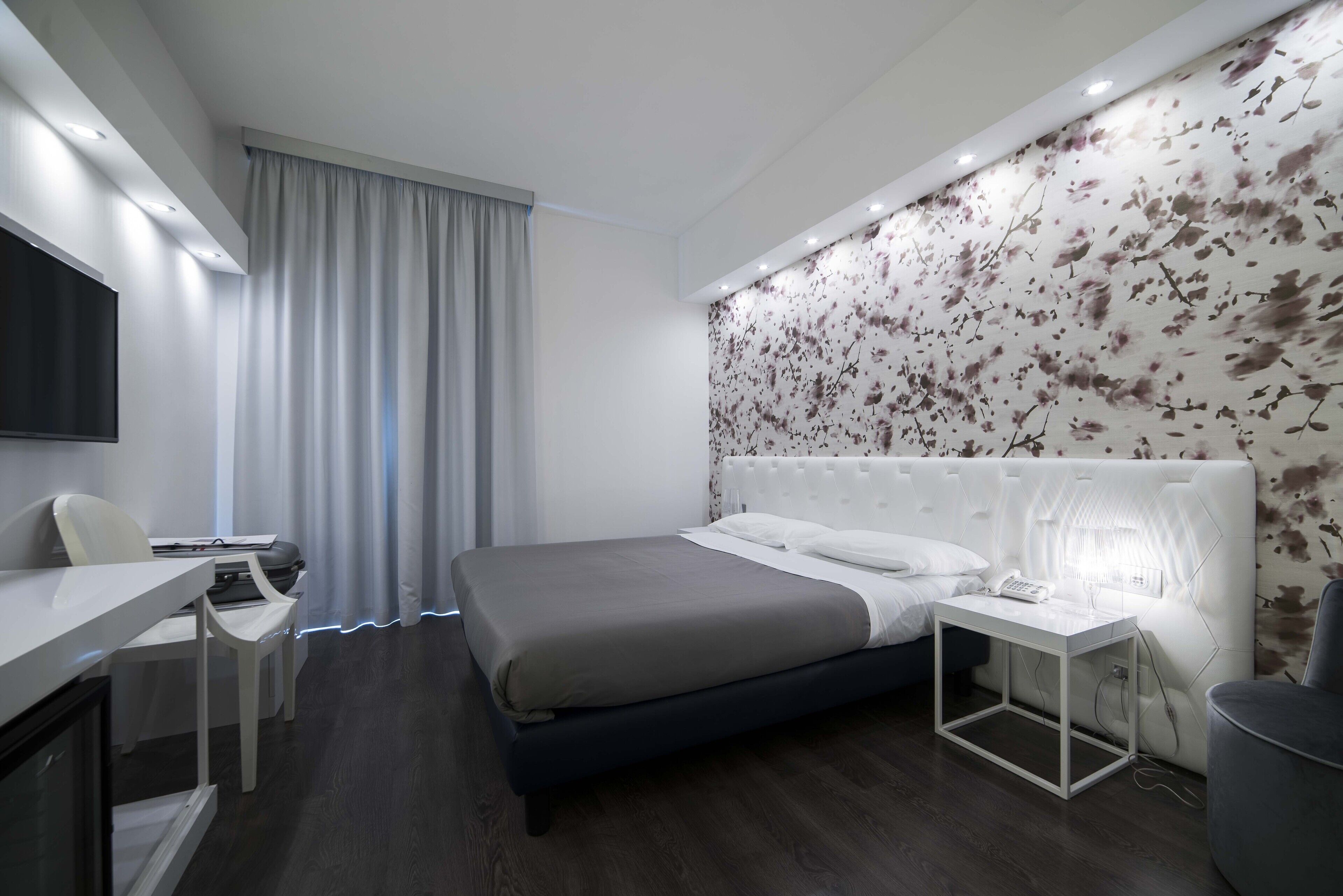 Une chambre d’hôtel moderne équipée d’un lit, d’une table de chevet, d’un bureau et d’une chaise.