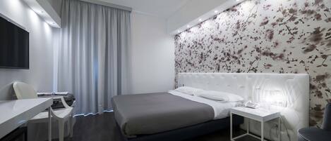 Ein modernes Hotelzimmer mit Bett, Nachttisch, Schreibtisch und Stuhl.