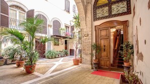 A courtyard with potted plants, a red carpet, and a wooden staircase leading to an entrance. - Navona Gallery Suites (Rome)