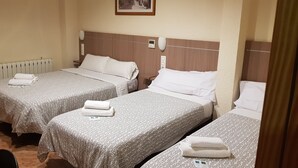 Une chambre d’hôtel avec deux lits, chacun agrémenté d’une serviette soigneusement pliée et d’une couvre-lit à motifs.