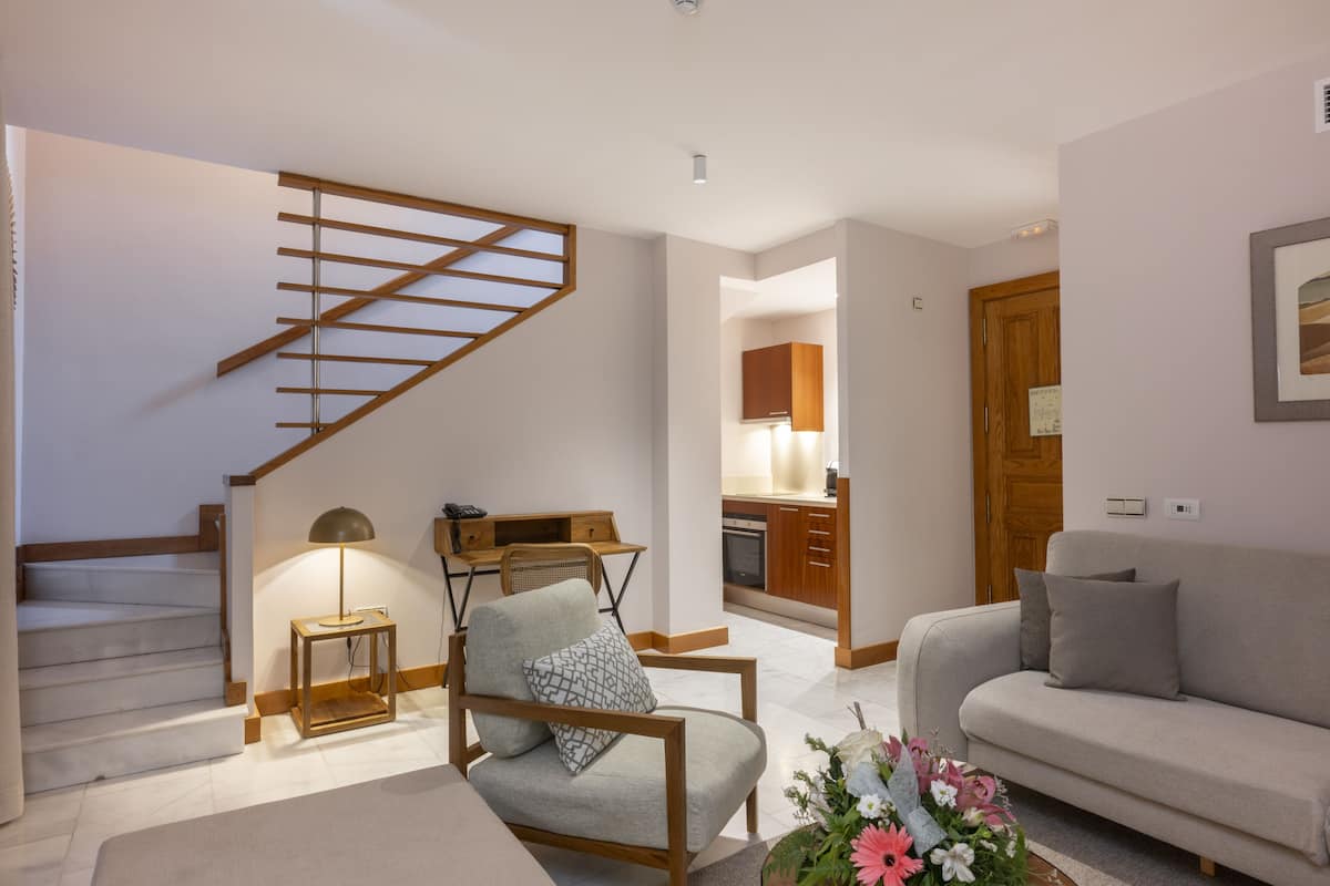 Una sala de estar moderna con una escalera, un sofá, una silla y un comedor.