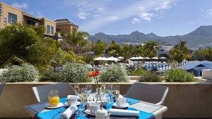 Mesa lista con vajilla blanca y una jarra de jugo de naranja, con vistas a un paisaje montañoso.