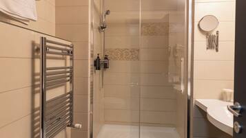 Een moderne badkamer met een douchecabine van glas, een wit toilet, een handdoekhouder en een wastafel met spiegel.