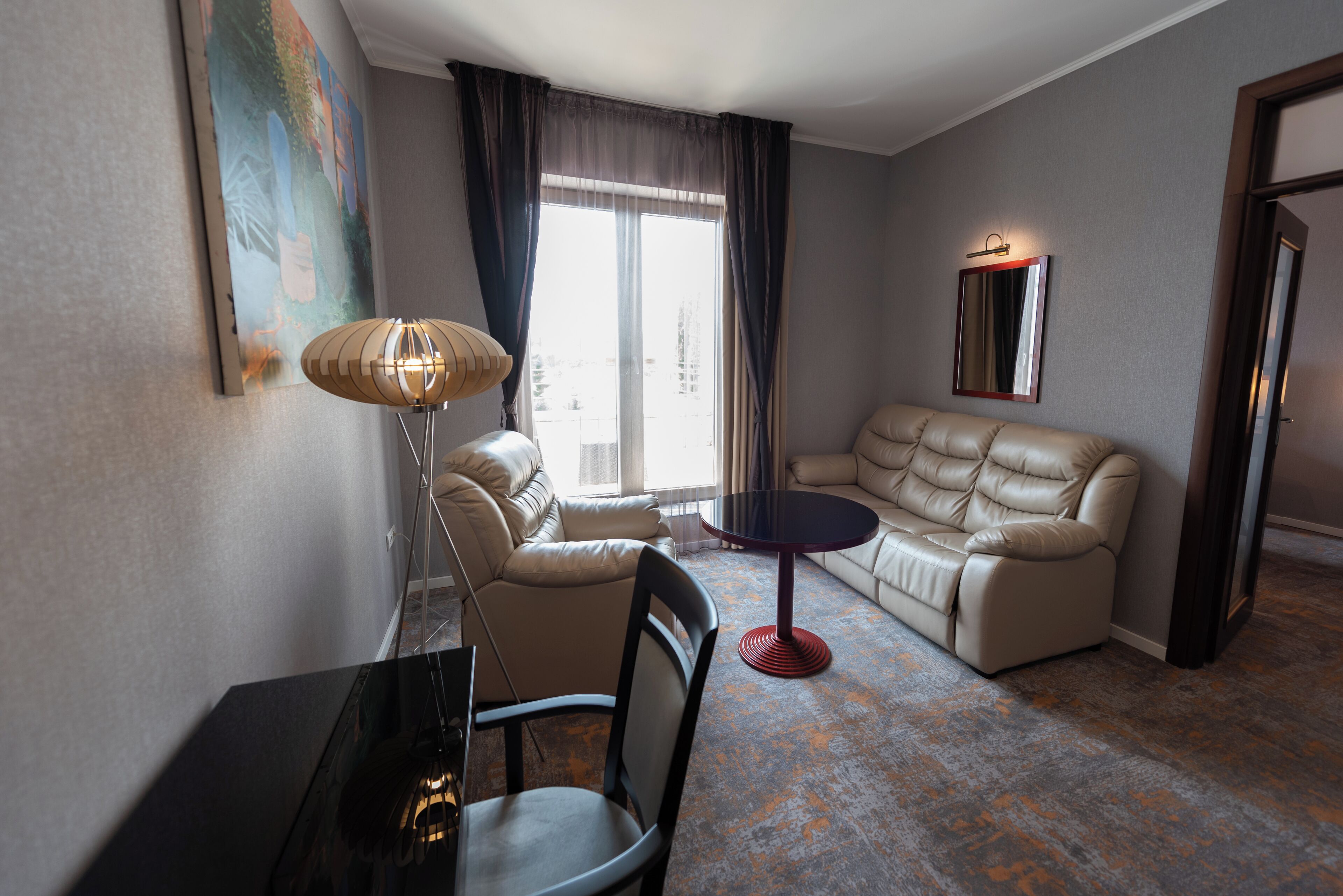 Une chambre d’hôtel moderne, équipée d’un canapé, d’un fauteuil et d’une petite table.