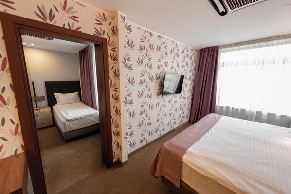 A hotel room with a bed, a TV, and a window with curtains. - Wyndham Cluj (Cluj-Napoca)