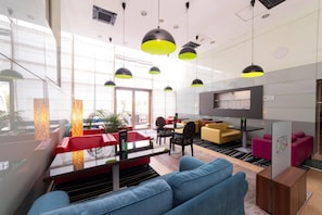 A modern lounge area with seating, a bar, and a television screen. - Wyndham Cluj (Cluj-Napoca)