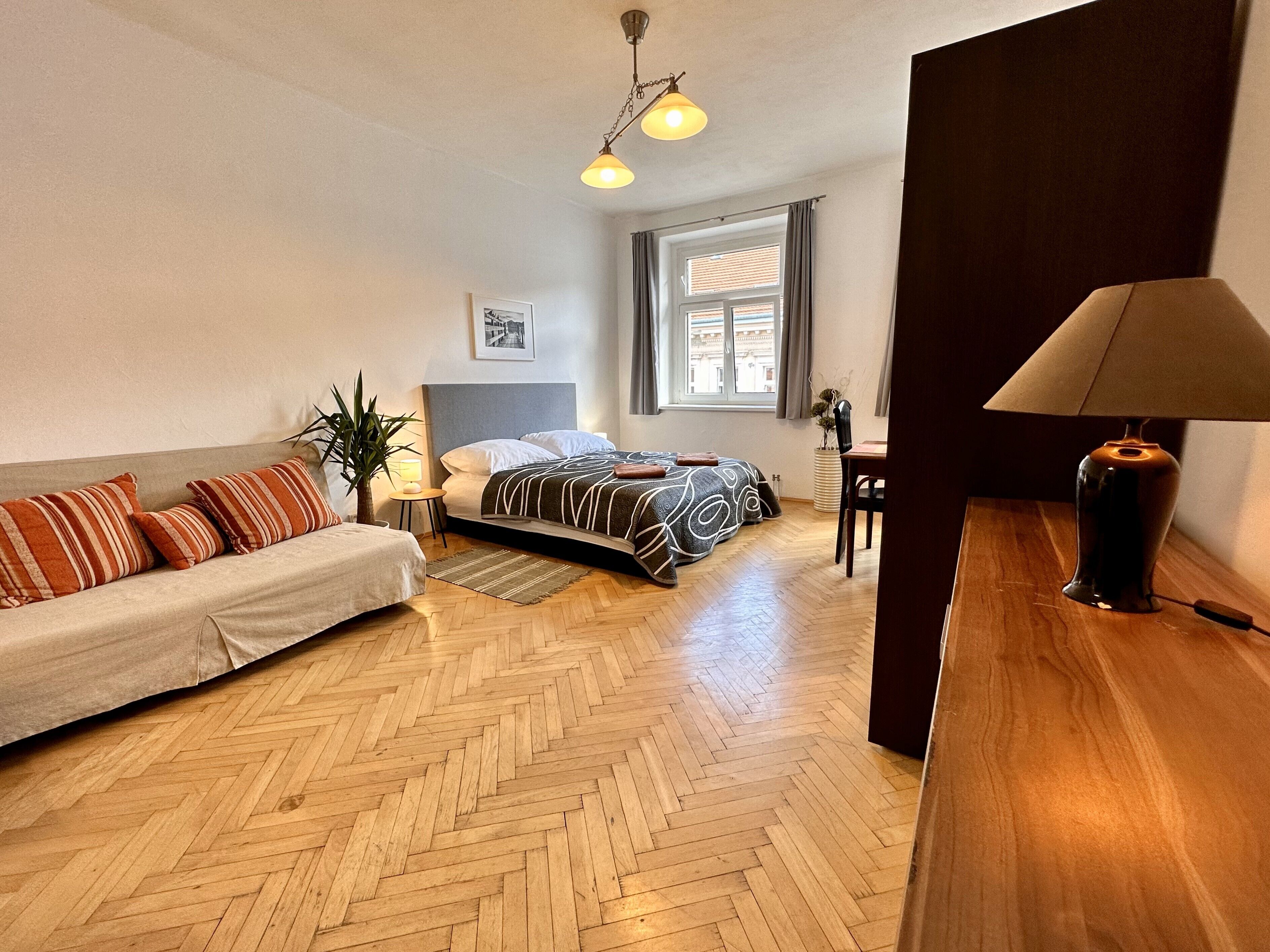 Una habitación con una cama, un sofá, un escritorio y una lámpara.
