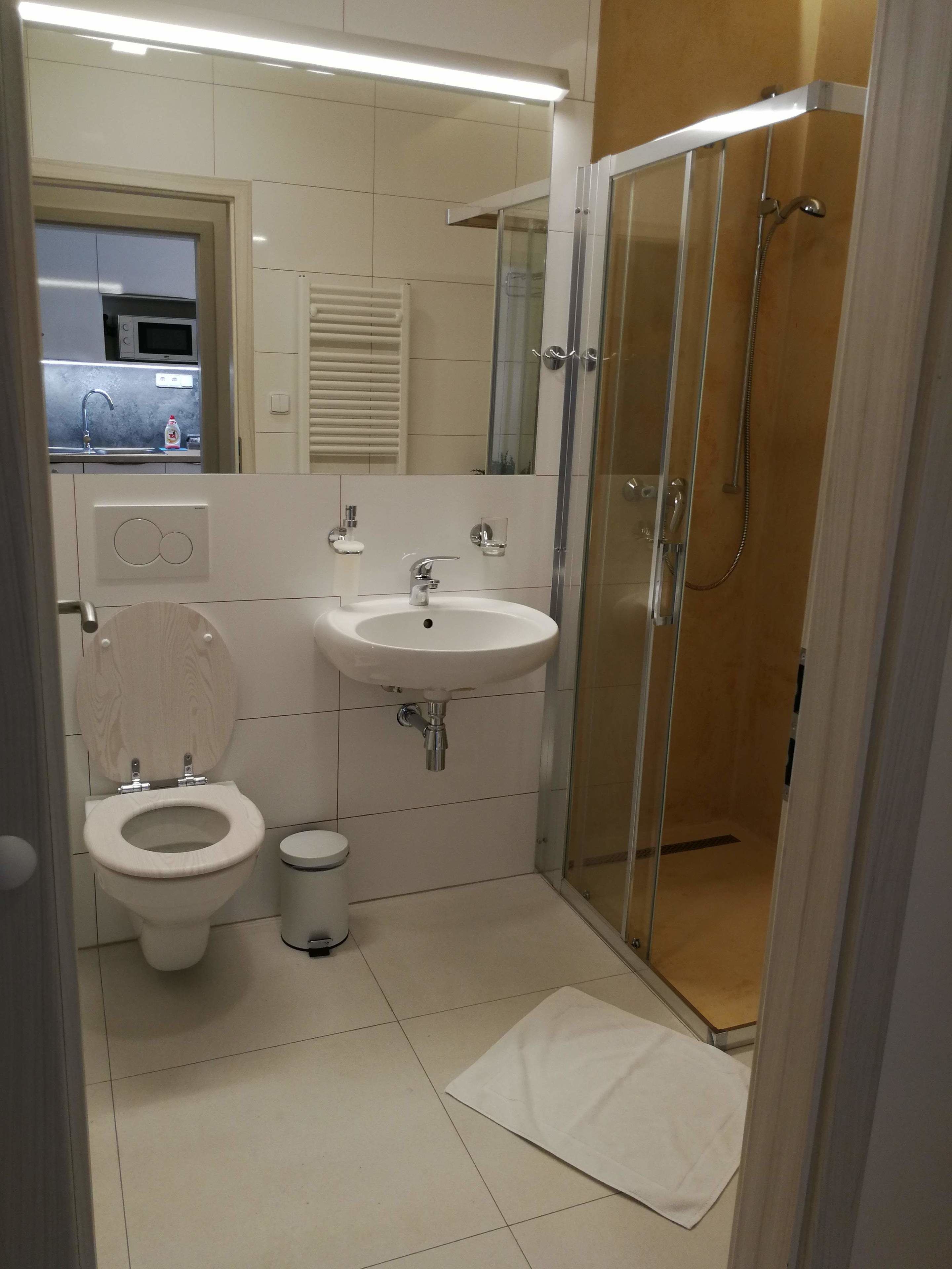 A compact bathroom with a toilet, sink, and glass-enclosed shower.