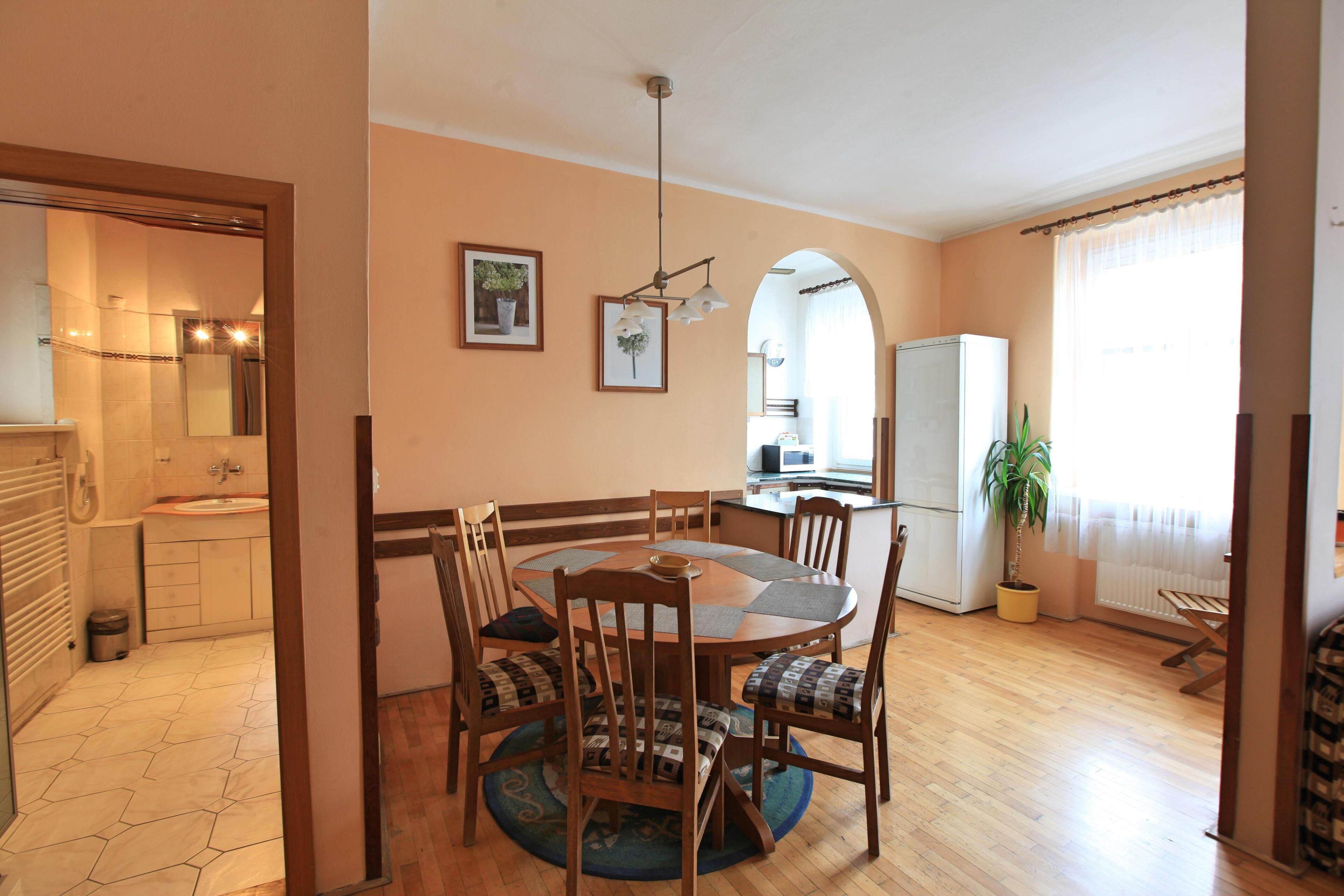 A dining area with a round table, wooden chairs, and a central light fixture.
