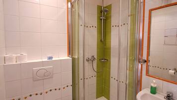 Une salle de bain avec une douche à parois de verre, des toilettes, un lavabo et un miroir.