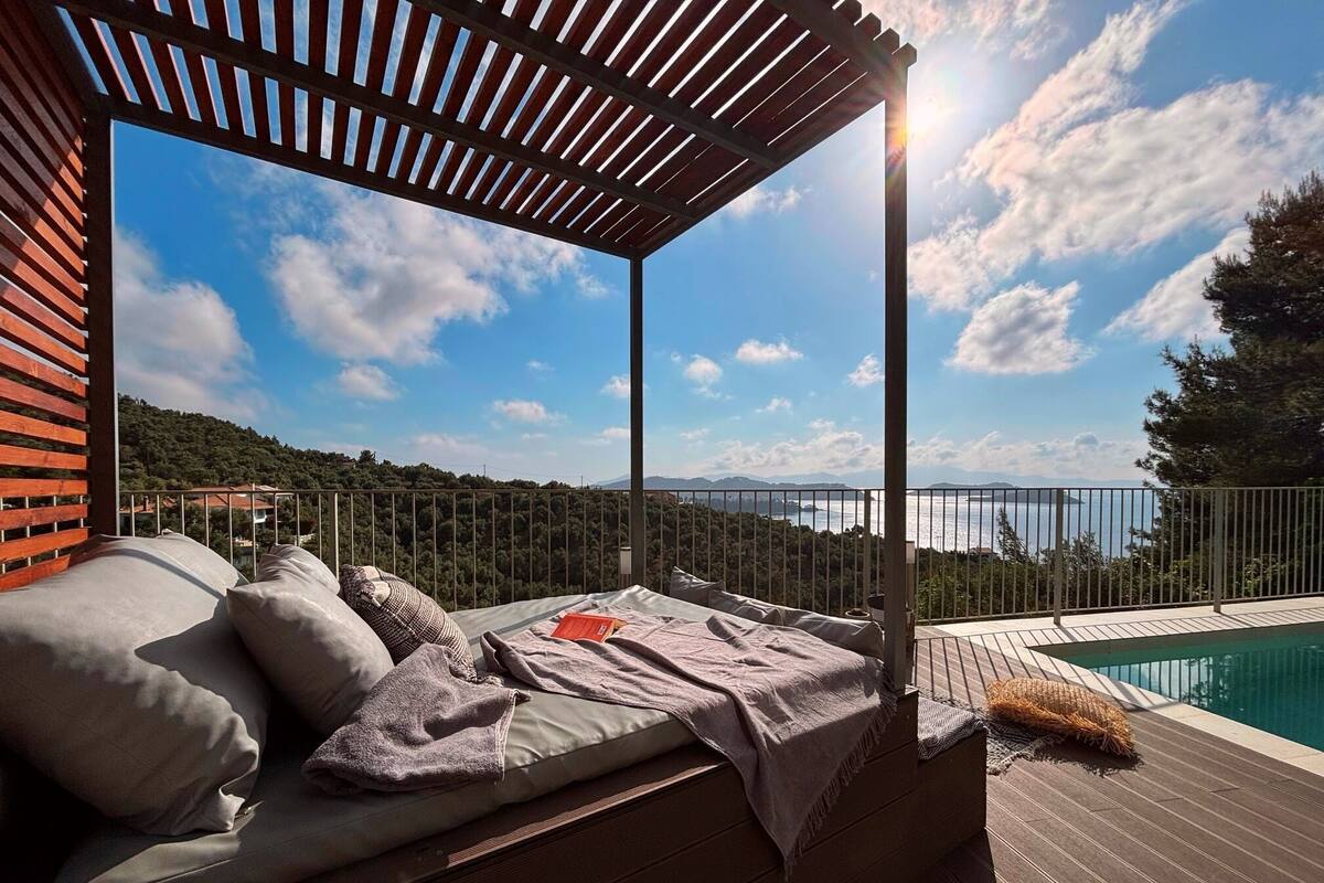 A sunlit outdoor seating area with a view of a body of water and hills.