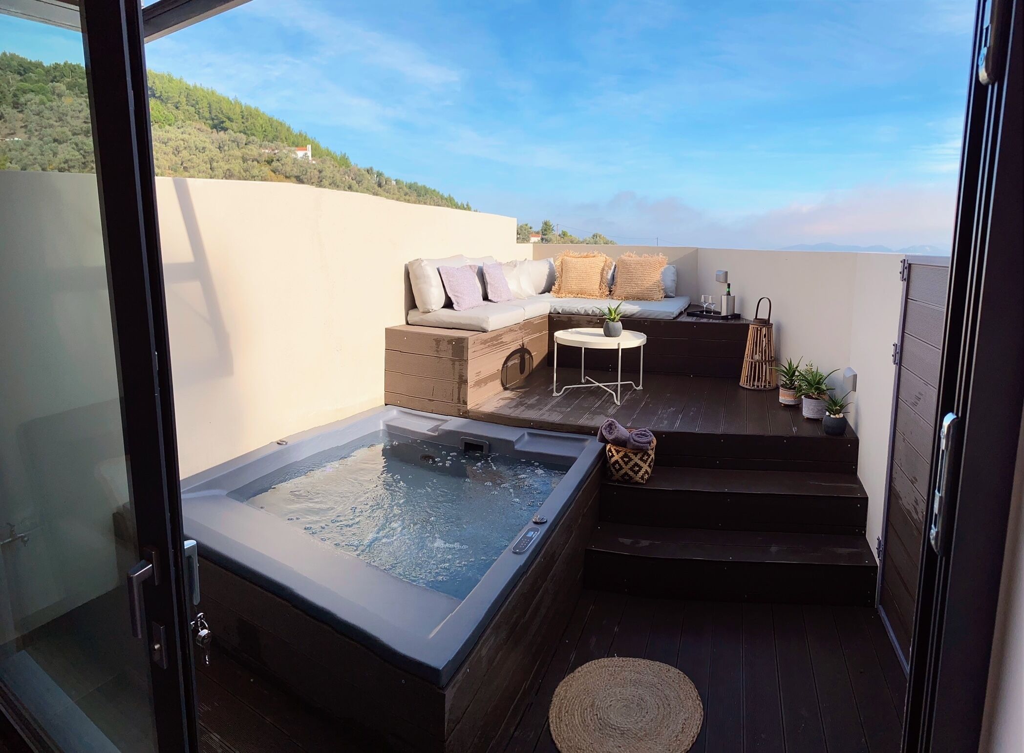 Une terrasse sur le toit équipée d’un jacuzzi, d’un espace salon et de plantes en pot.