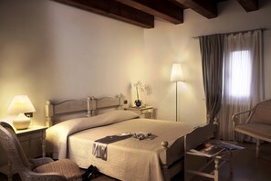 Relax in a classic hotel room with a large bed, bedside table, and comfortable chair.