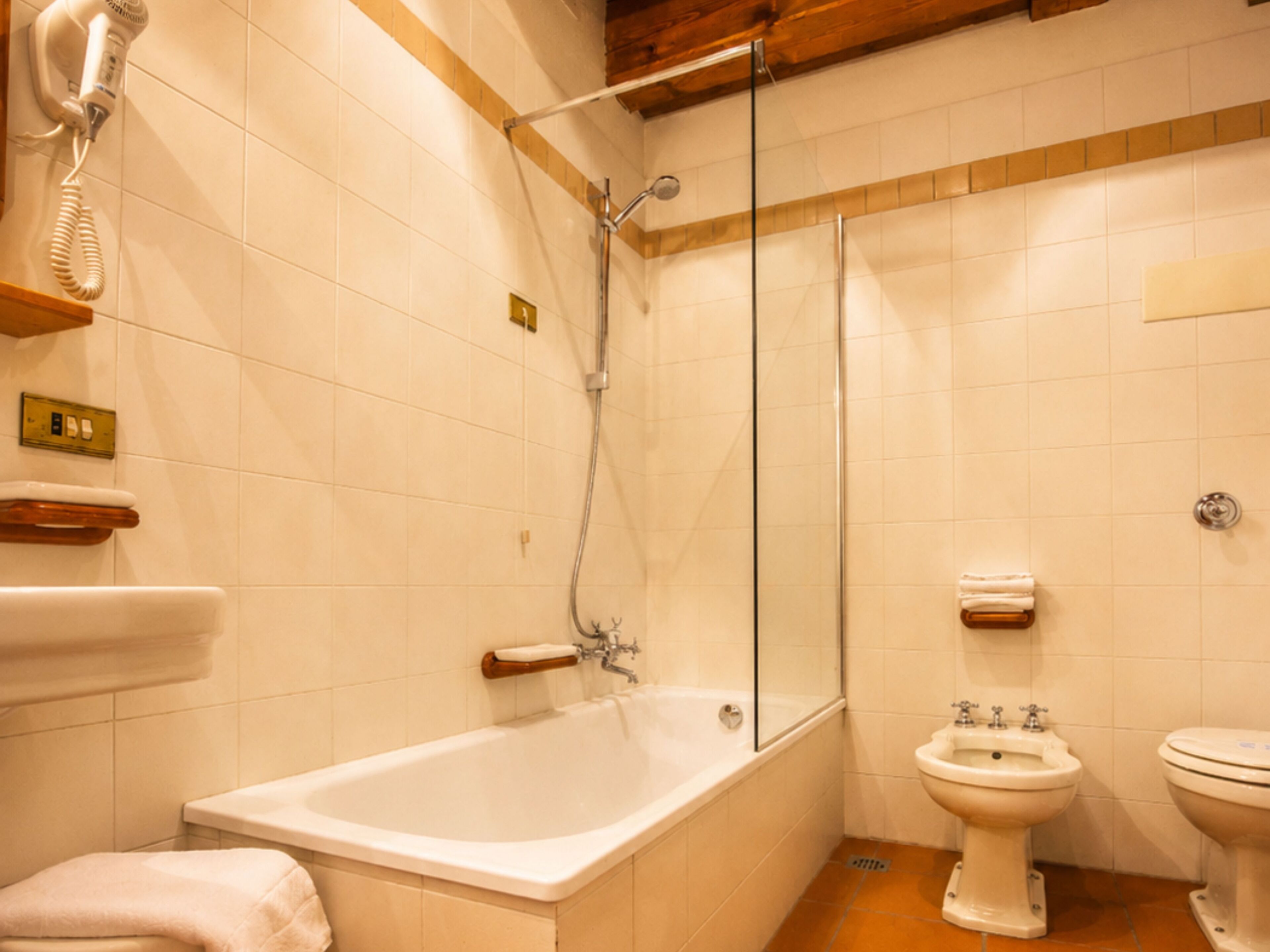 A bathroom with a bathtub, a shower, a toilet, and a bidet.