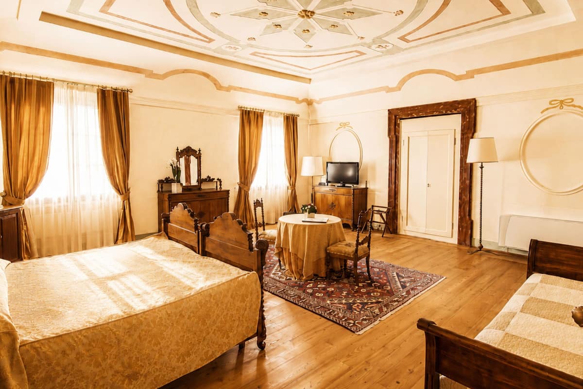 Une chambre d’hôtel avec un lit, un bureau, une télévision, un miroir et une porte.