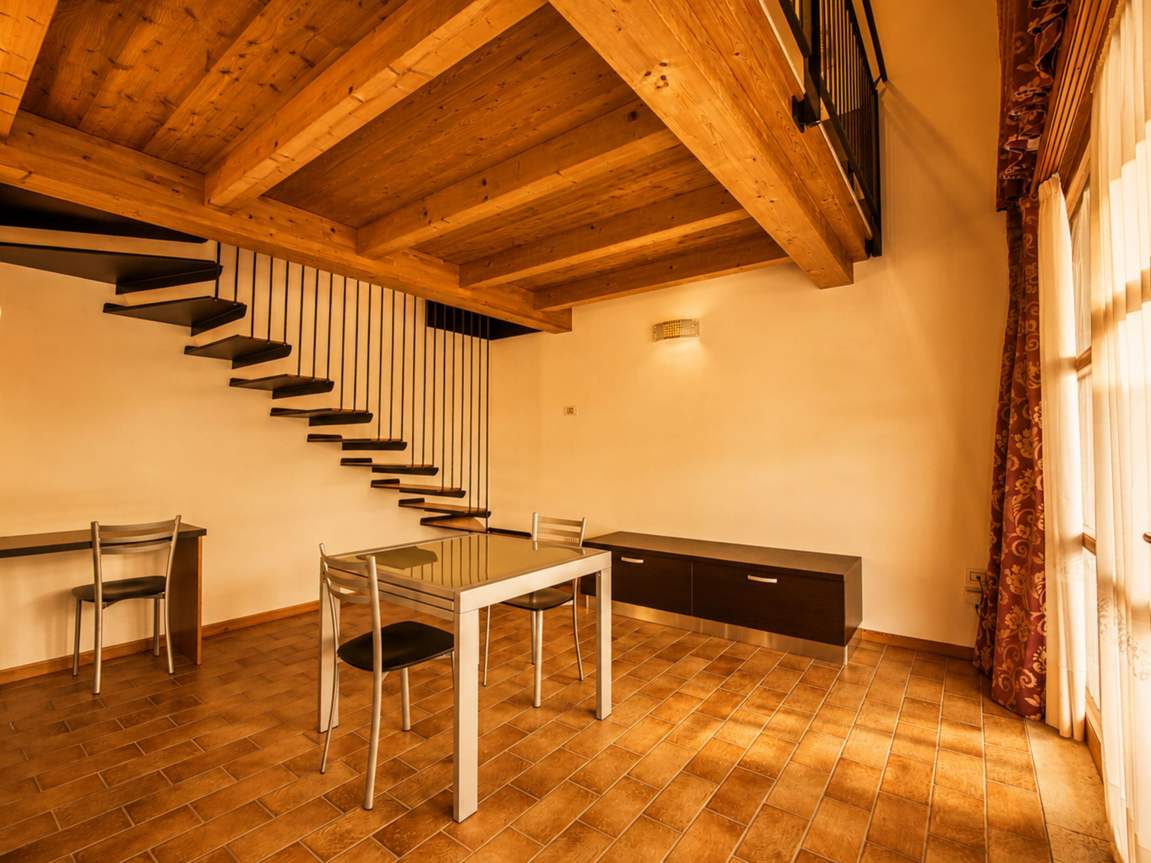Un rincón comedor con una escalera, una mesa, sillas y un armario.