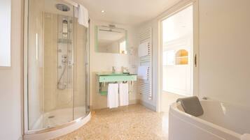 A bathroom with a glass-enclosed shower, a green vanity, a white bathtub, and a door leading to another room.