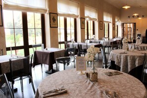 Enjoy a formal dining experience in this elegant space with large windows, white tablecloths, and framed artwork.