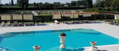 Piscina com espreguiçadeiras e um pérgola.