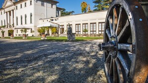 A building with a large wheel, gravel ground, and potted plants.