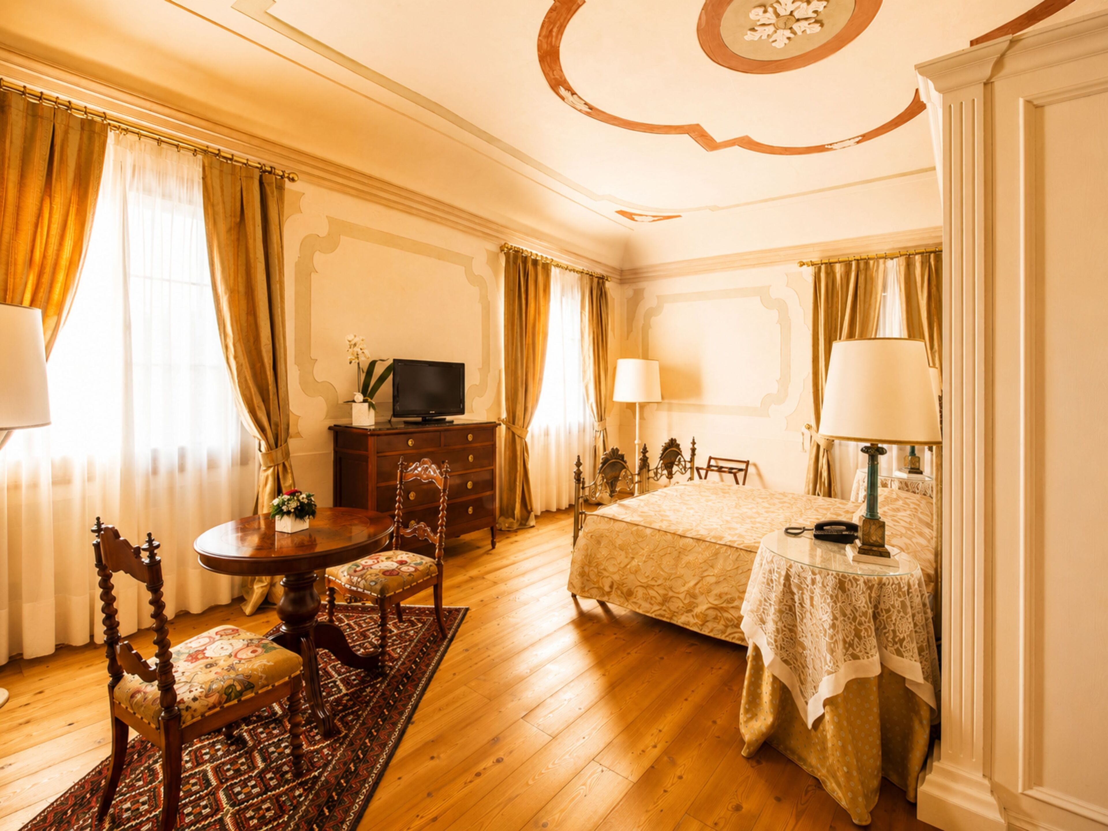Une chambre d’hôtel comprenant un lit, un bureau avec une télévision, une chaise, une table et une lampe.