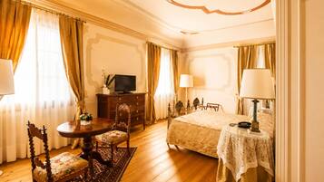 Une chambre d’hôtel comprenant un lit, un bureau avec une télévision, une chaise, une table et une lampe.