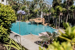 Una piscina al aire libre, sombrillas, tumbonas