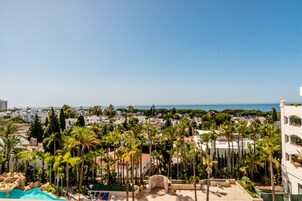 A resort with a pool, palm trees, and a view of the sea.