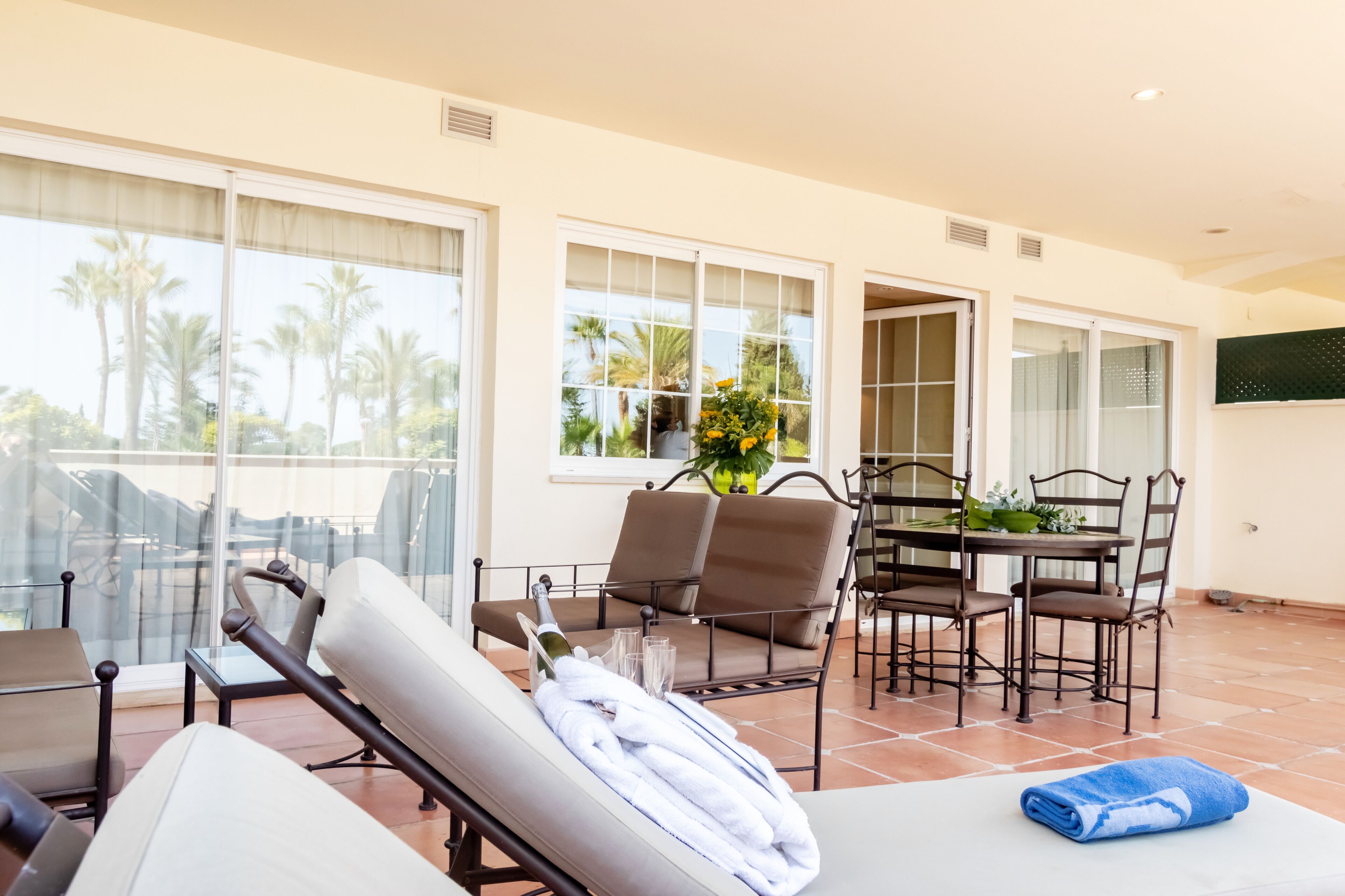 A spacious room with a balcony, a dining area, and a lounge area with a massage chair and towels.