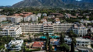A coastal town with a prominent mountain in the background, featuring a mix of residential and hotel buildings with balconies and some greenery. - Guadalpin Suites (Marbella)