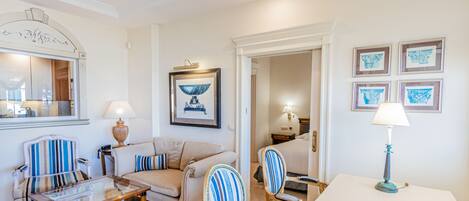 Un salon bien éclairé, avec une table basse en verre, des fauteuils à rayures, un canapé et une table à manger agrémentée d’une lampe.