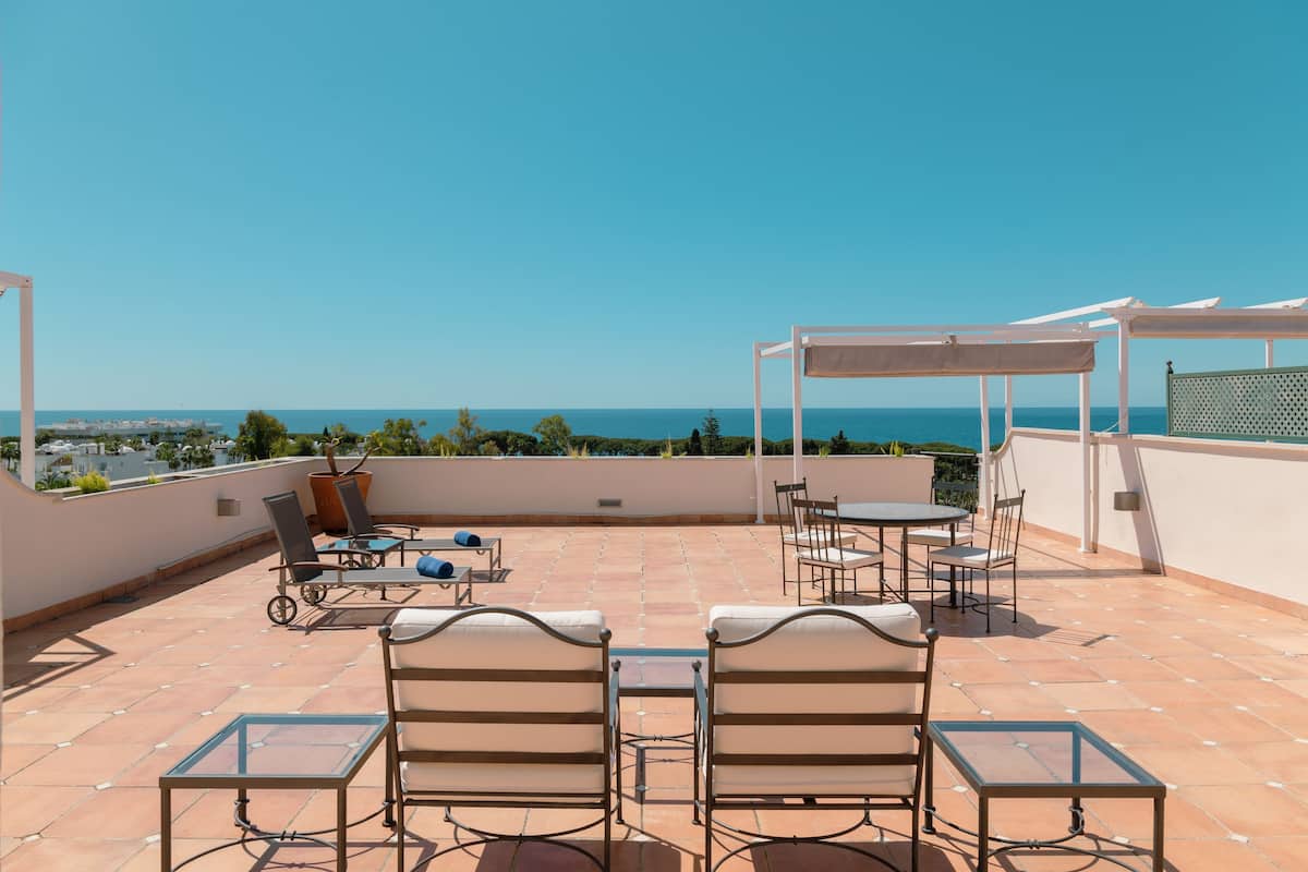 A rooftop terrace with outdoor seating, a pergola, and a view of the sea.