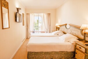 Een hotelkamer met twee bedden, een televisie, een lamp en uitzicht op de omgeving.