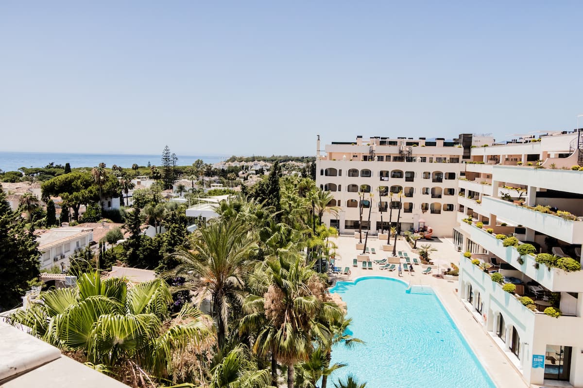 A hotel with a pool, multiple balconies, and a view of the sea.