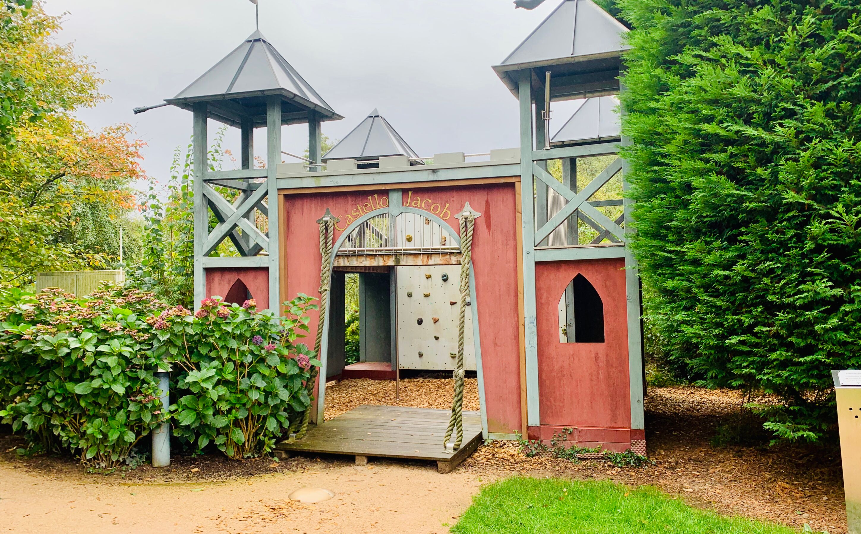 A castle-like structure with a central archway, wooden steps, and a rope on the right side.