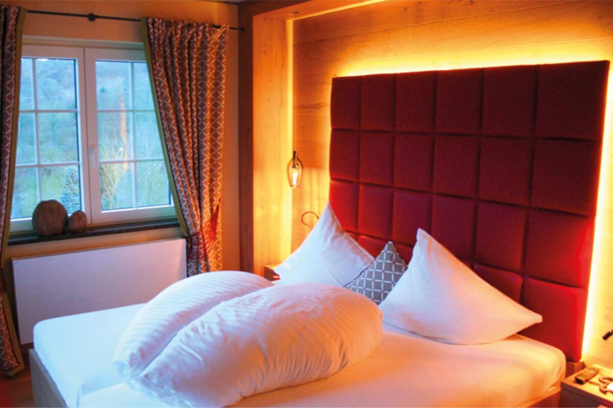 Ein Schlafzimmer mit einem großen Bett, einem Fenster mit Vorhängen und einem roten Kopfteil.